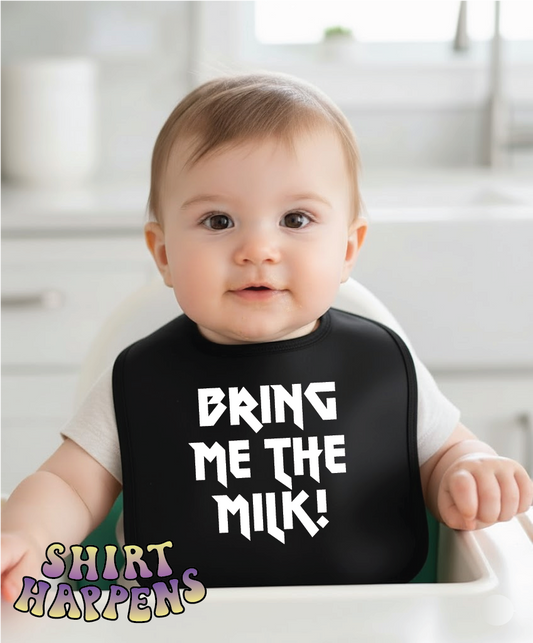 Baby wearing a black bib with 'BRING ME THE MILK!' text, sitting in a high chair.